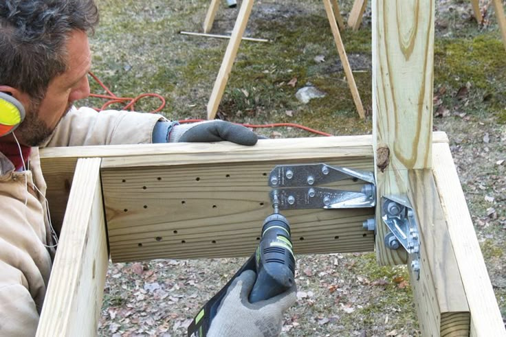 a man is working on some wood in the yard with a drill and screwdriver