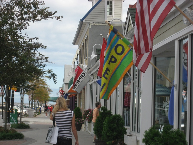 a woman is walking down the street carrying shopping bags and an american flag on her head