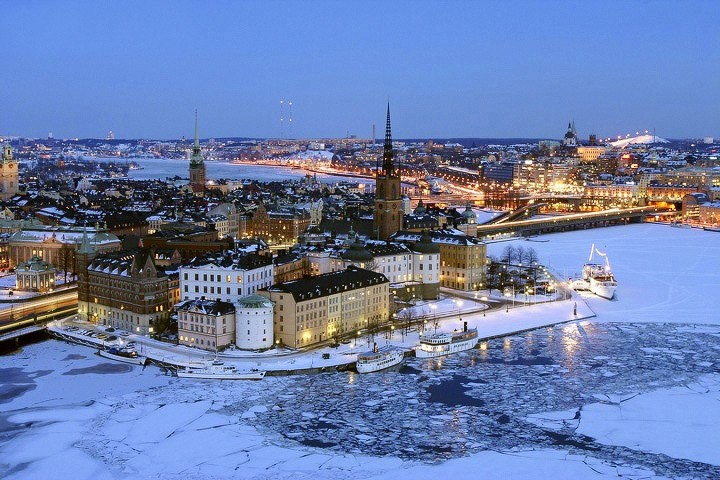 an aerial view of a city at night with ice on the water and buildings in the background