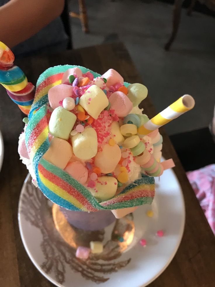 a colorful ice cream sundae on a white plate with candy and marshmallows