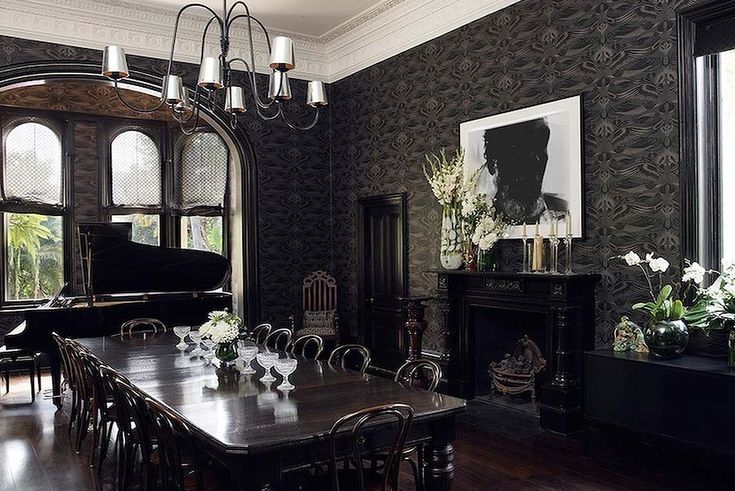 an elegant dining room with black walls and wood flooring, large chandelier