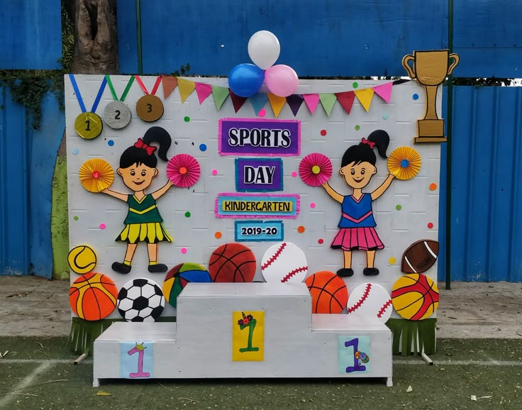 a sports day display in front of a blue wall with balloons and decorations on it