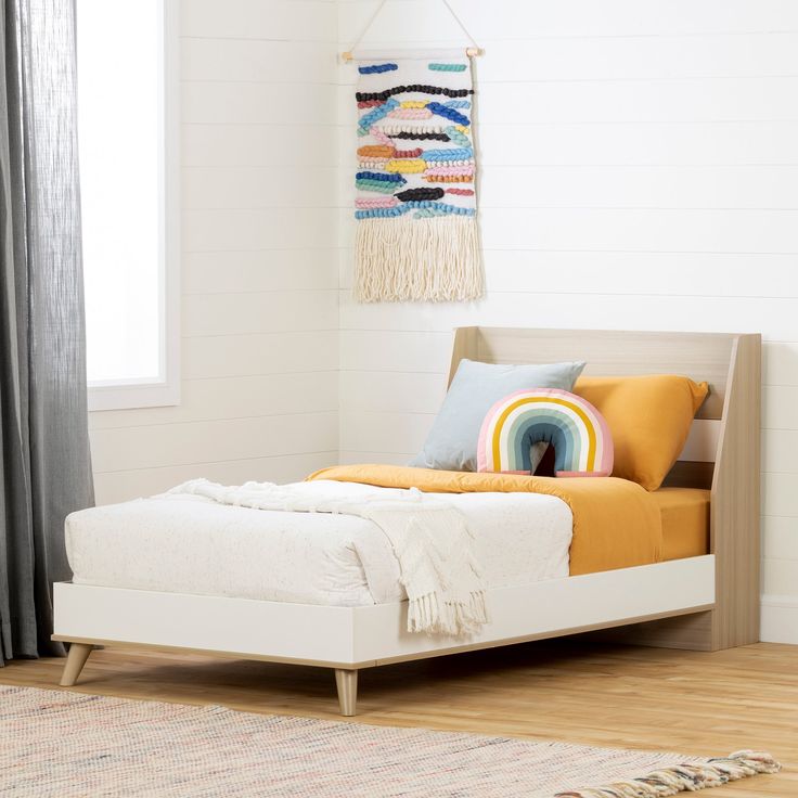 a white bed sitting in a bedroom on top of a hard wood floor next to a window