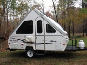 a camper trailer parked in the woods with its awning open and it's bed pulled up