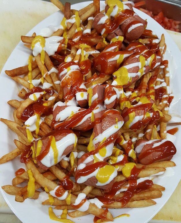 a white plate topped with french fries covered in ketchup and cheese on top