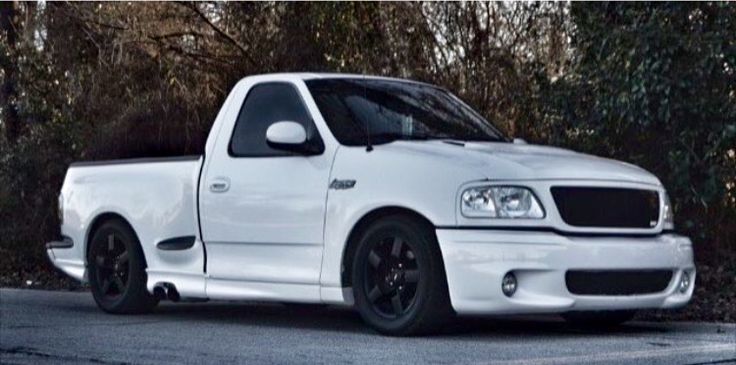 a white pick up truck parked in front of some trees