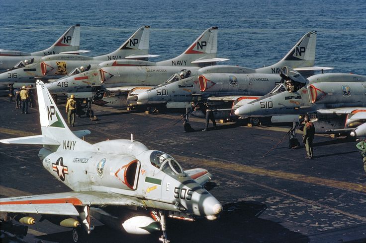 fighter jets lined up on the deck of an aircraft carrier