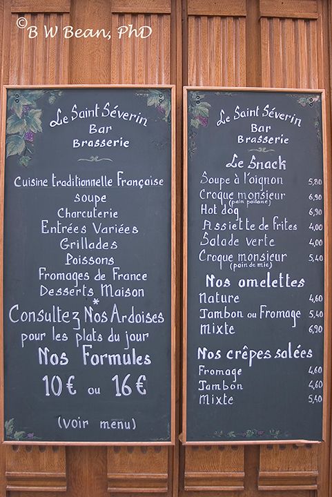 two menu boards on the side of a building with wood paneling and wooden slats