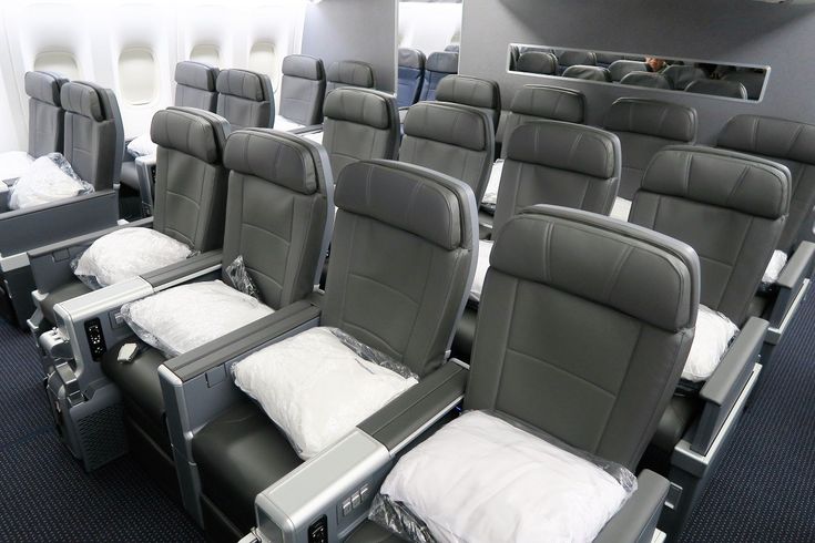 rows of empty seats in an airplane with blue carpeting and white pillows on them