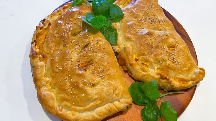 how to make calzonee on a wooden cutting board with fresh herbs and leaves