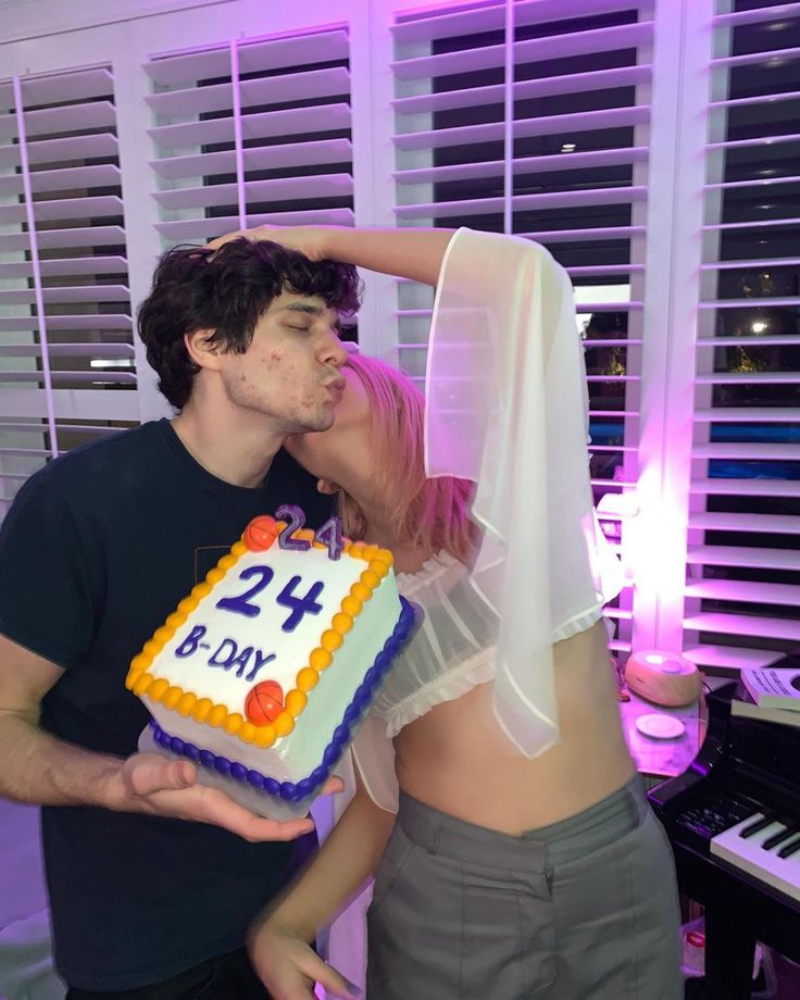 a man and woman kissing in front of a cake with the number 24 on it