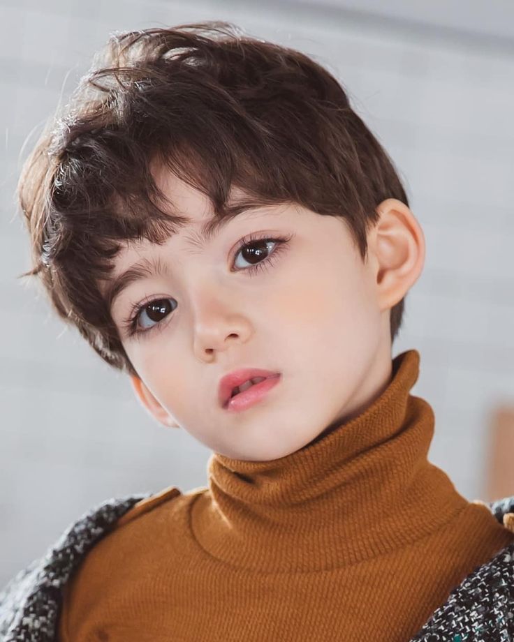 a young boy with brown hair wearing a turtle neck sweater