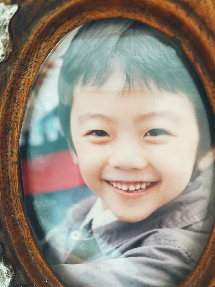 a young boy with blue hair is smiling for the camera in a wooden framed photo