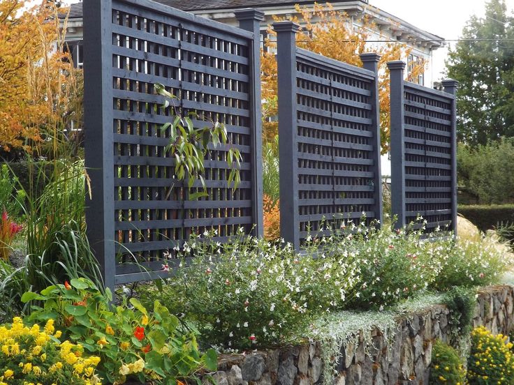 a garden with many different types of flowers and plants around it, including an ornamental trellis