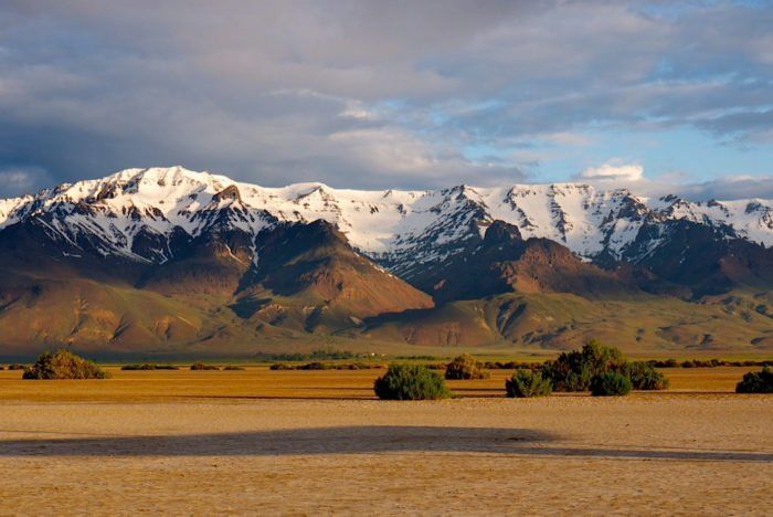 the mountains are covered in snow and brown grass