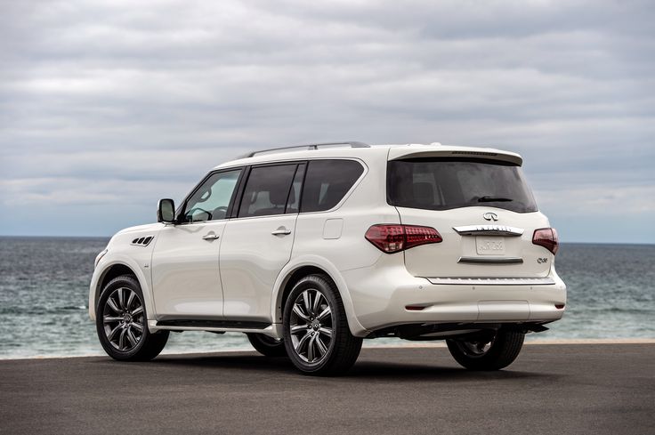 the rear end of a white infiniti parked near the ocean