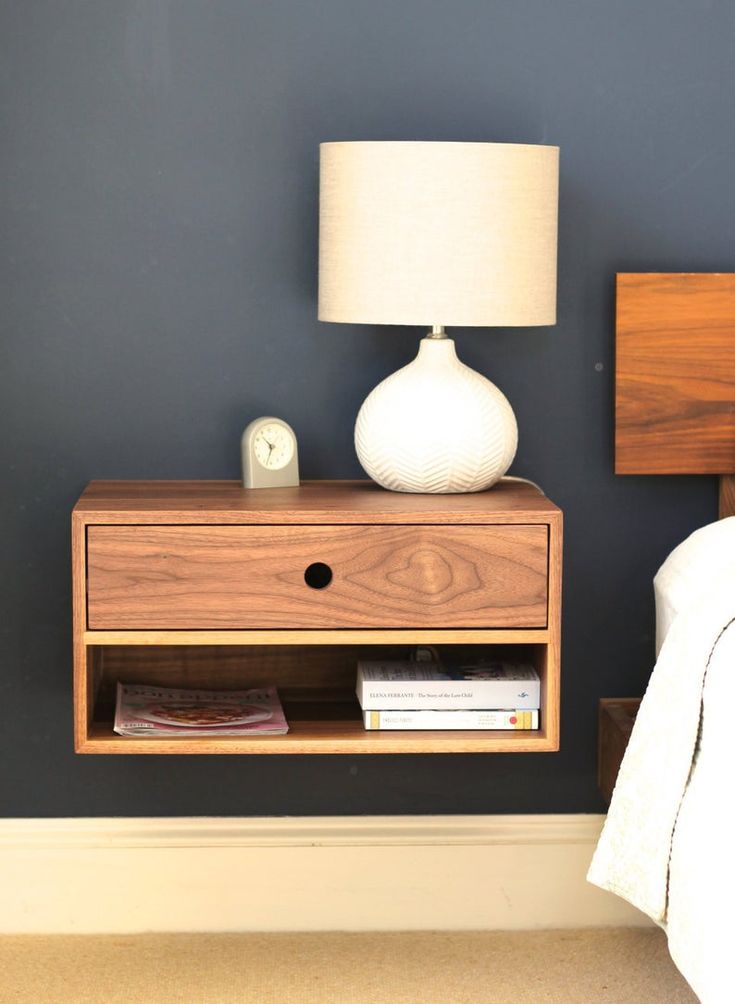 a nightstand with a lamp on it next to a bed