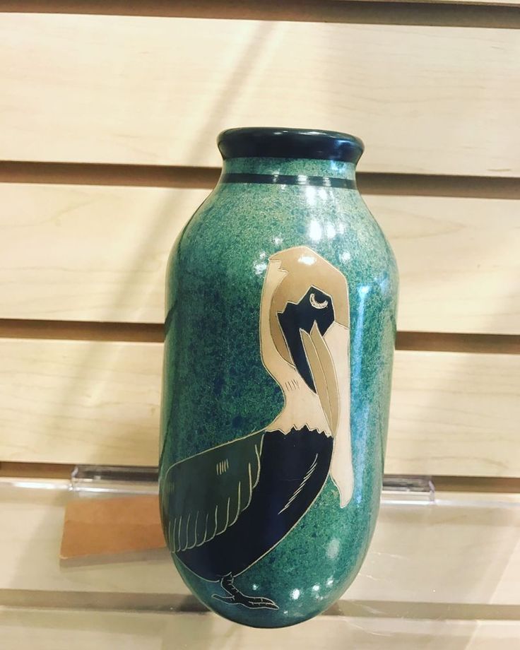 a blue vase with a bird painted on it's side sitting on a shelf