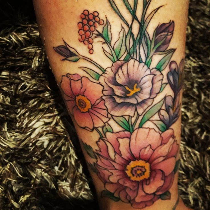 a close up of a person's leg with flowers and berries on the side