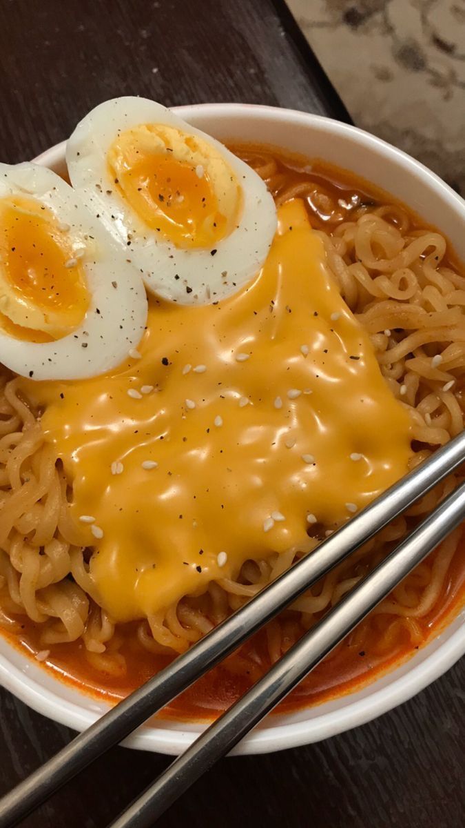 a bowl of noodles with two boiled eggs on top