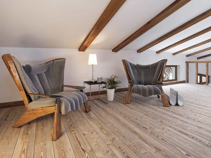 two chairs and a table in a room with wood flooring on one side and exposed beams on the other