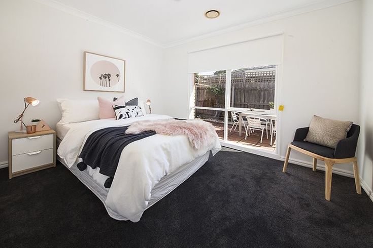 a bed room with a neatly made bed next to a sliding glass door and a chair