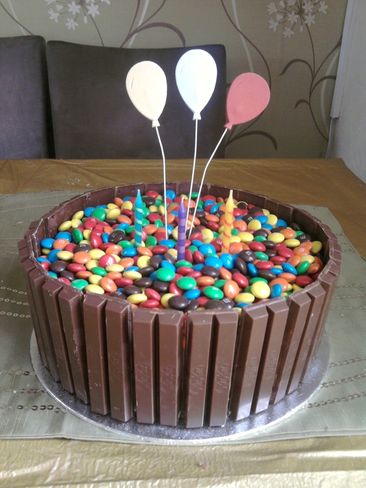 a chocolate cake topped with candy and balloons