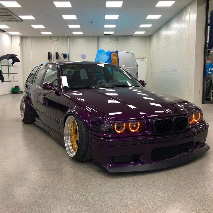 a purple car parked in a garage with its lights on and it's hood up