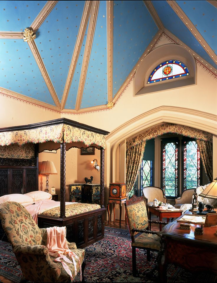 a bedroom with a canopy bed, desk and chairs in front of a stained glass window