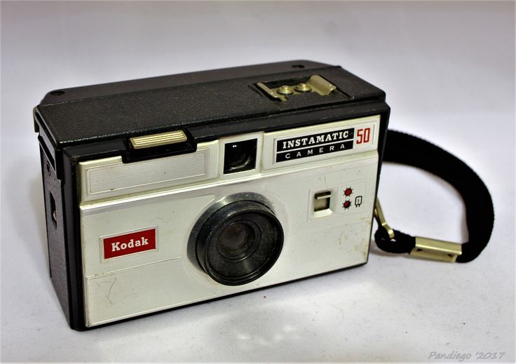 an old kodak camera sitting on top of a white table next to a black strap