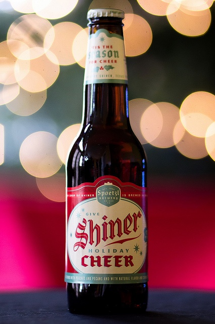 a bottle of beer sitting on top of a table next to a blurry background