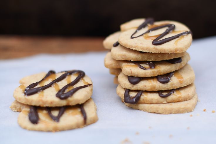 a stack of cookies with chocolate drizzled on them sitting on a table