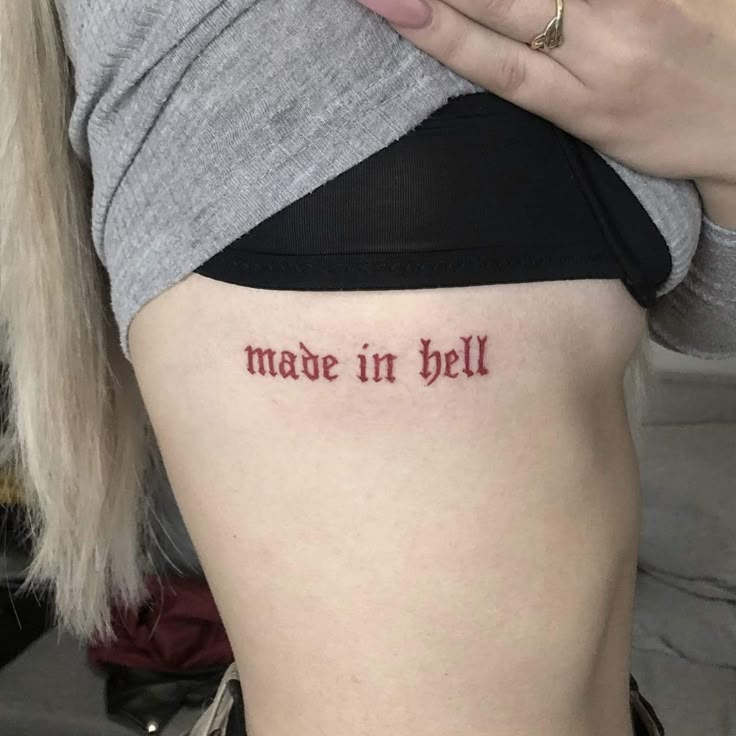 a woman with a tattoo that says made in hell on her side ribcage