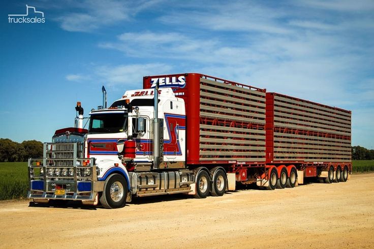 a red and white semi truck driving down a dirt road