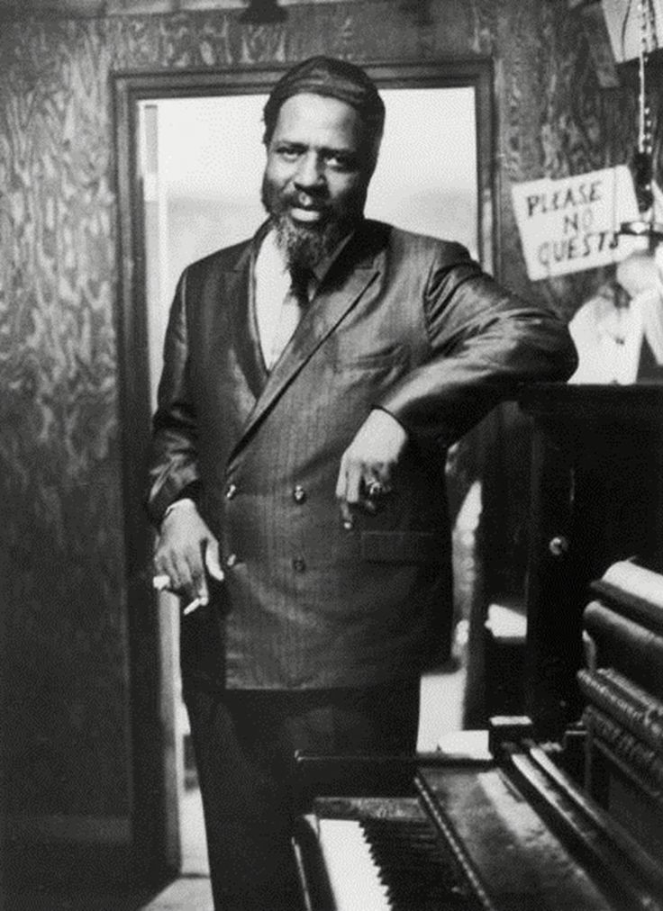 an old photo of a man standing next to a piano