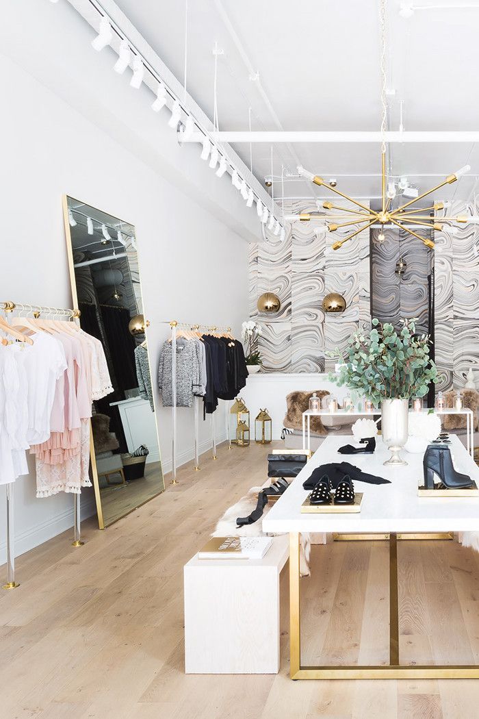 the inside of a clothing store with clothes and shoes on display in front of it