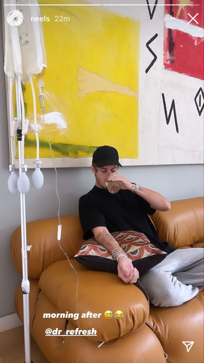 a man sitting on top of a brown leather chair next to a large yellow painting