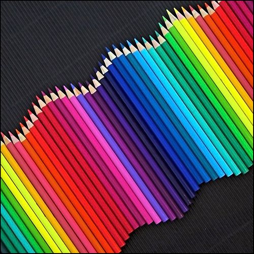 many colored pencils are lined up on a black surface