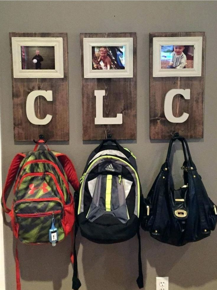 three backpacks are hanging on the wall next to two pictures and one has a name