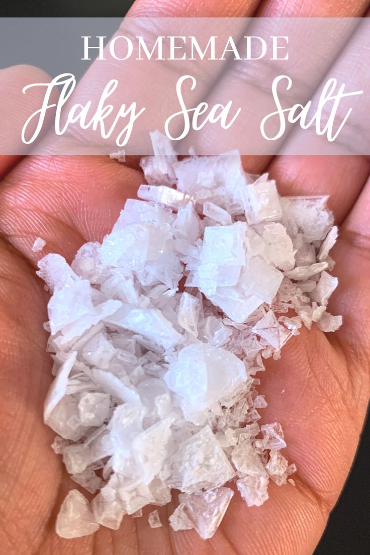 a hand holding some white flaky sea salt with the words homemade flaky sea salt