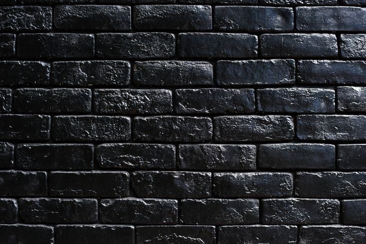 a black brick wall that is very dark and has some light coming from the top