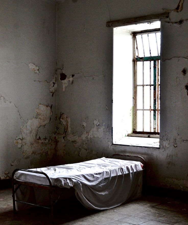 an empty bed sitting in front of a window