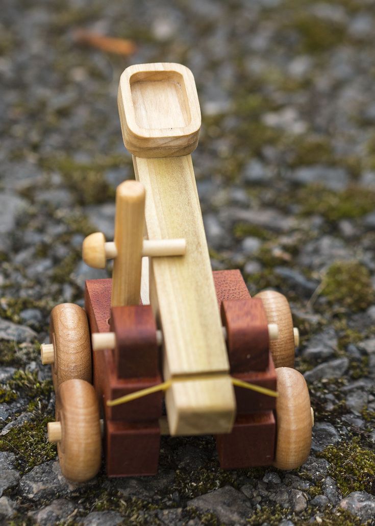 a toy car made out of wood sitting on the ground