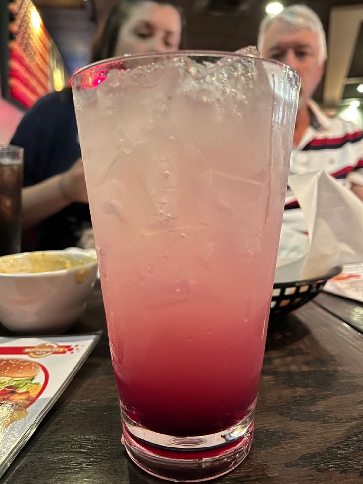 a pink drink sitting on top of a wooden table