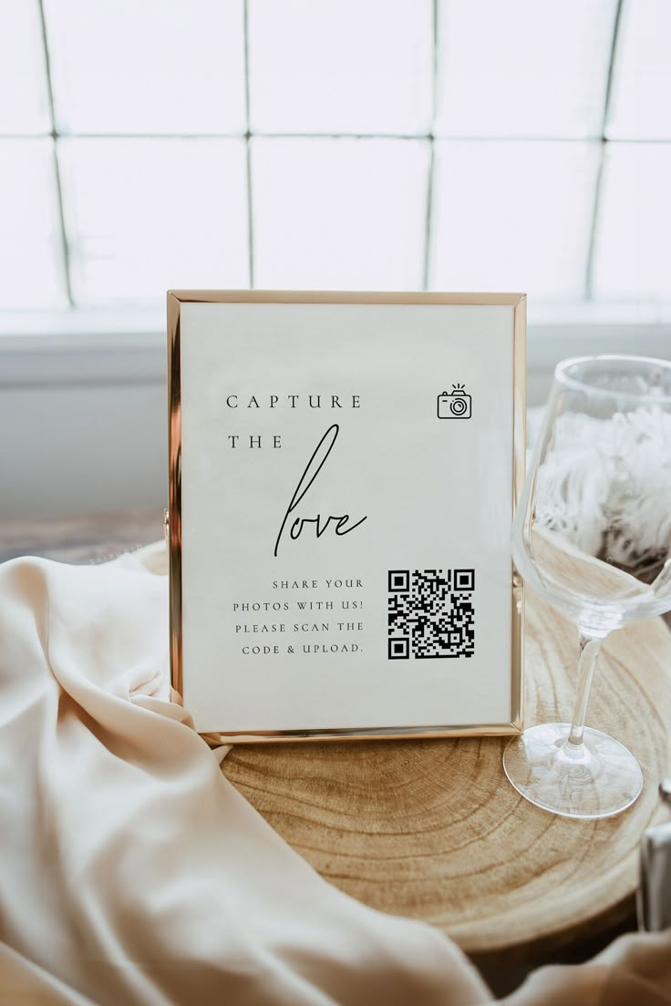 a wine glass sitting on top of a wooden table next to a sign that says capture the love