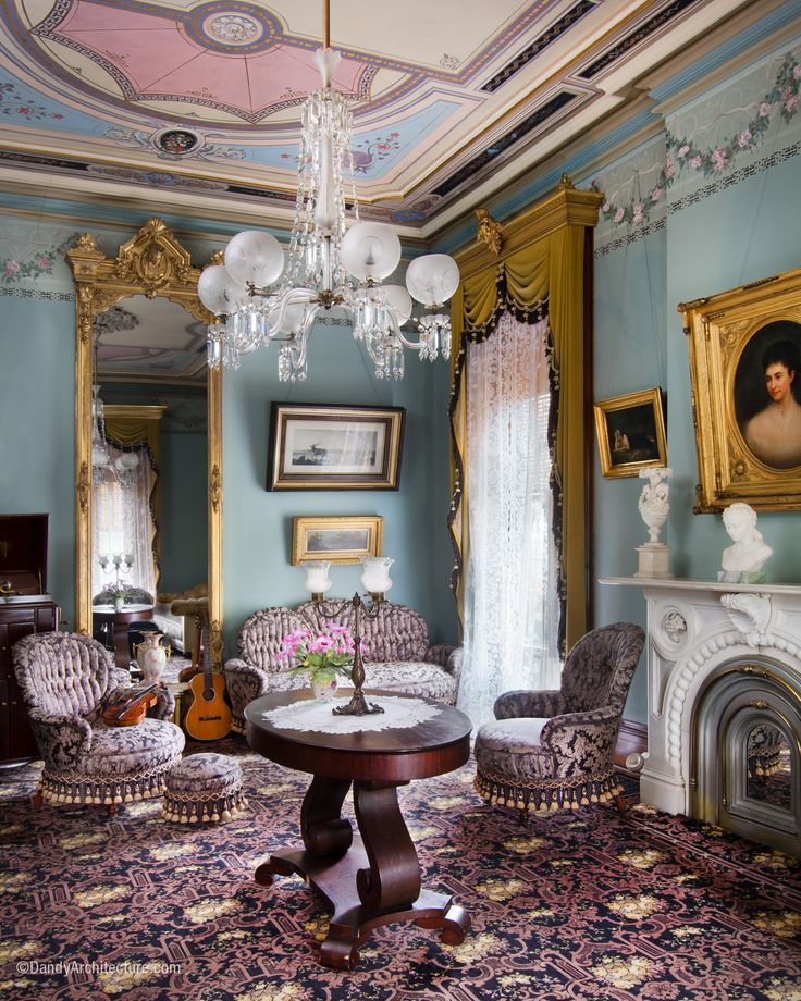 a living room filled with furniture and a chandelier hanging from the ceiling over a fire place