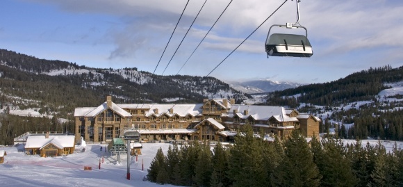 a ski lift is above a large building in the middle of a snowy mountain area