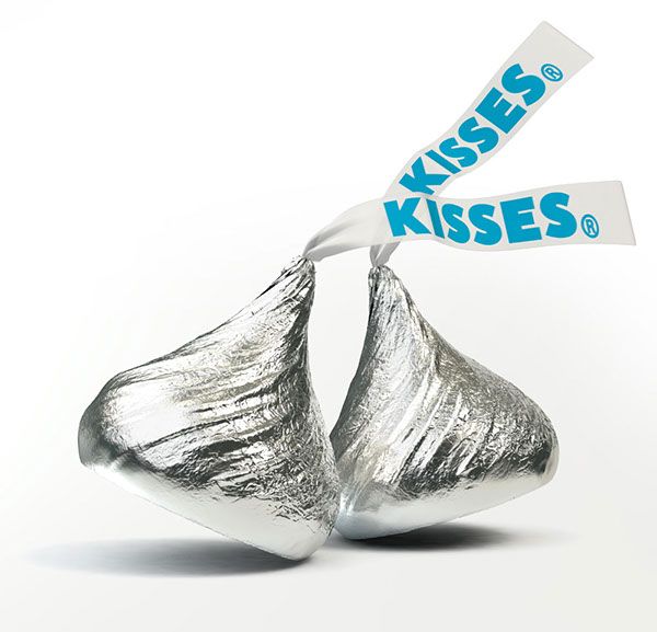 two pieces of silver foil wrapped in white paper with the word kisses on it's side