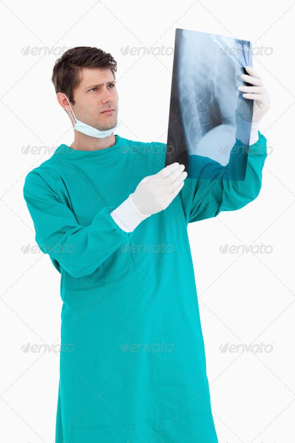 a man in scrubs holding up an x - ray