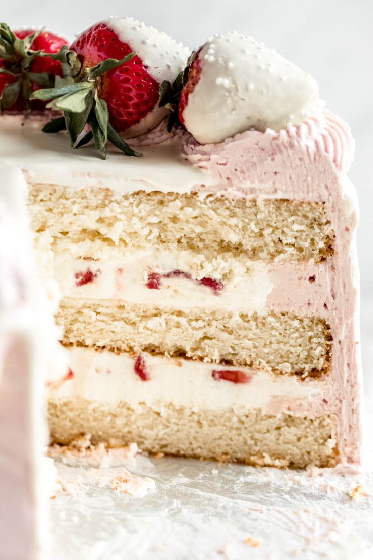 a piece of cake with strawberries on top and frosting in the middle is cut into pieces